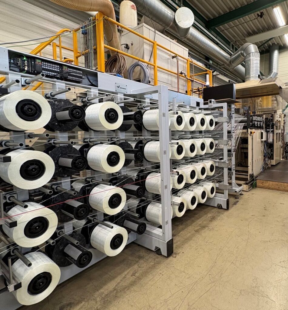 Van Wees glass roving creel with spoolholders for individual yarn tension measurement upstream of the UD600TPR thermoplastic resin impregnation line